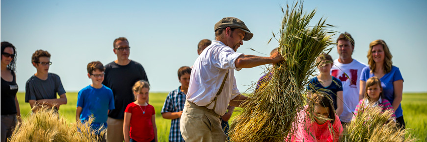 A man tying grain sheaves in front of a crowd.