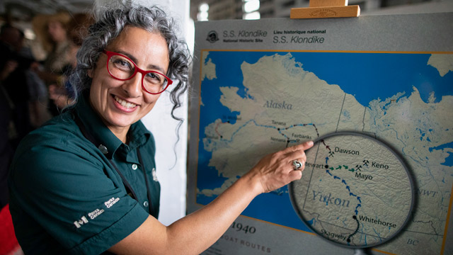 Smiling Parks Canada Heritage Interpreter showing map of Yukon Rivers
