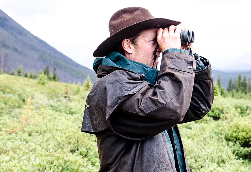 Le personnel de Parcs Canada regarde à travers des jumelles dans l'arrière-pays de Banff