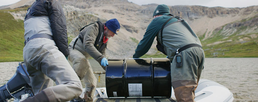 Team members load a barrel of Rotenone onto their boat