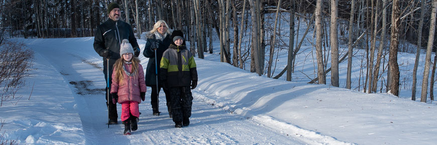 Family of four walks along a snowy trail