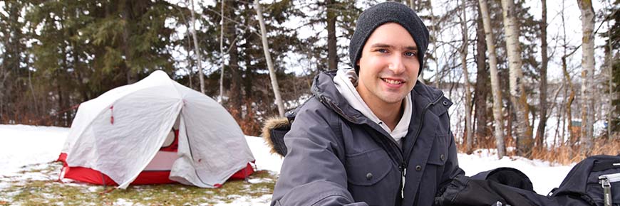 Man smiling next to tent in snow. 