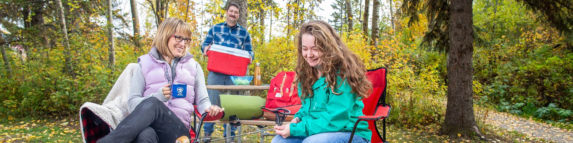 De jeunes adultes font un pique-nique et un feu de camp par une journée d’automne au camping du lac Astotin, dans le parc national Elk Island. 