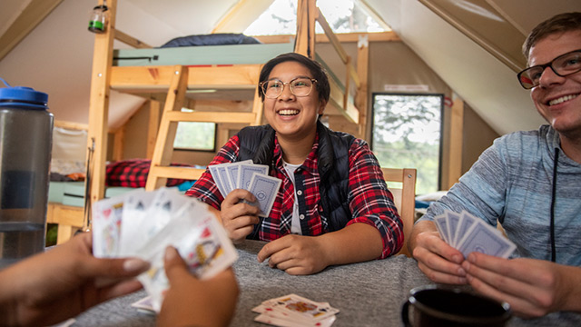 Des campeurs jouent aux cartes dans un abri oTENTik de Parcs Canada... Parc national Elk Island