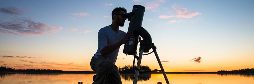 Un homme regarde dans un télescope pointé vers le ciel.
