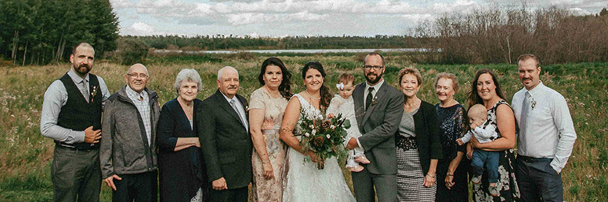 A wedding with less than 25 guests takes photos along the banks of Astotin Lake.
