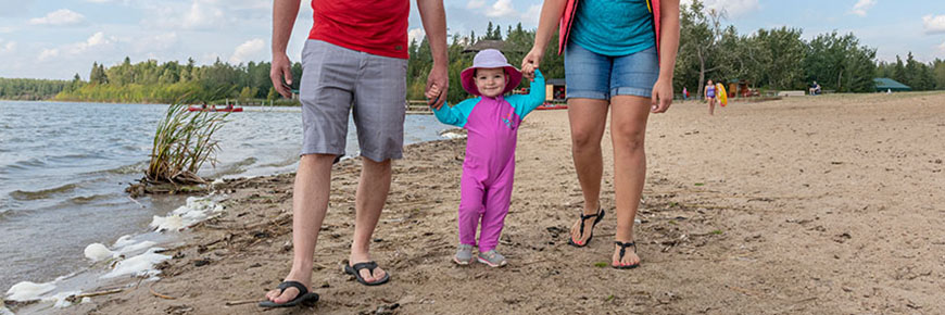Jeune enfant tenant les mains des parents au bord du lac Atotin