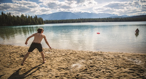 Young man throwing a frisbee on a beach