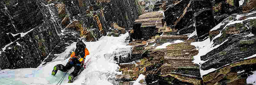 A climber ascends a frozen waterfall