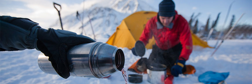 A winter camper pours a hot drink