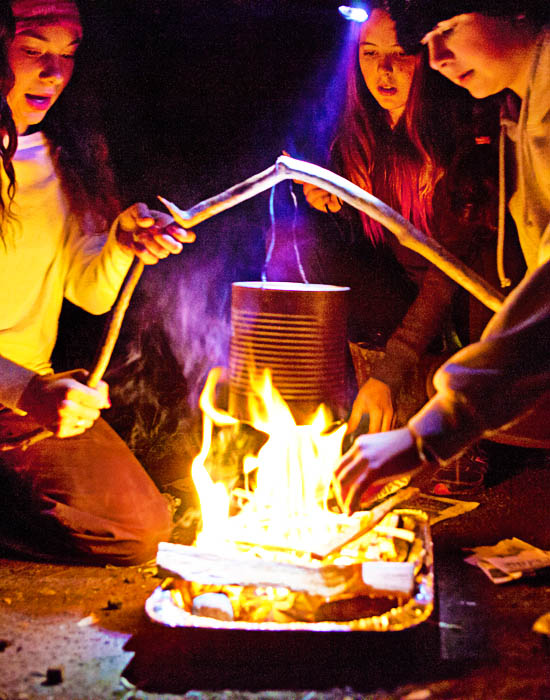 Des étudiants font bouillir de l’eau dans un pot sur le feu de camp.