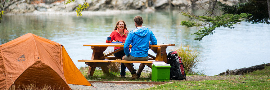 People sit at a picnic table at their campsite at Shingle Bay, Pender Island.