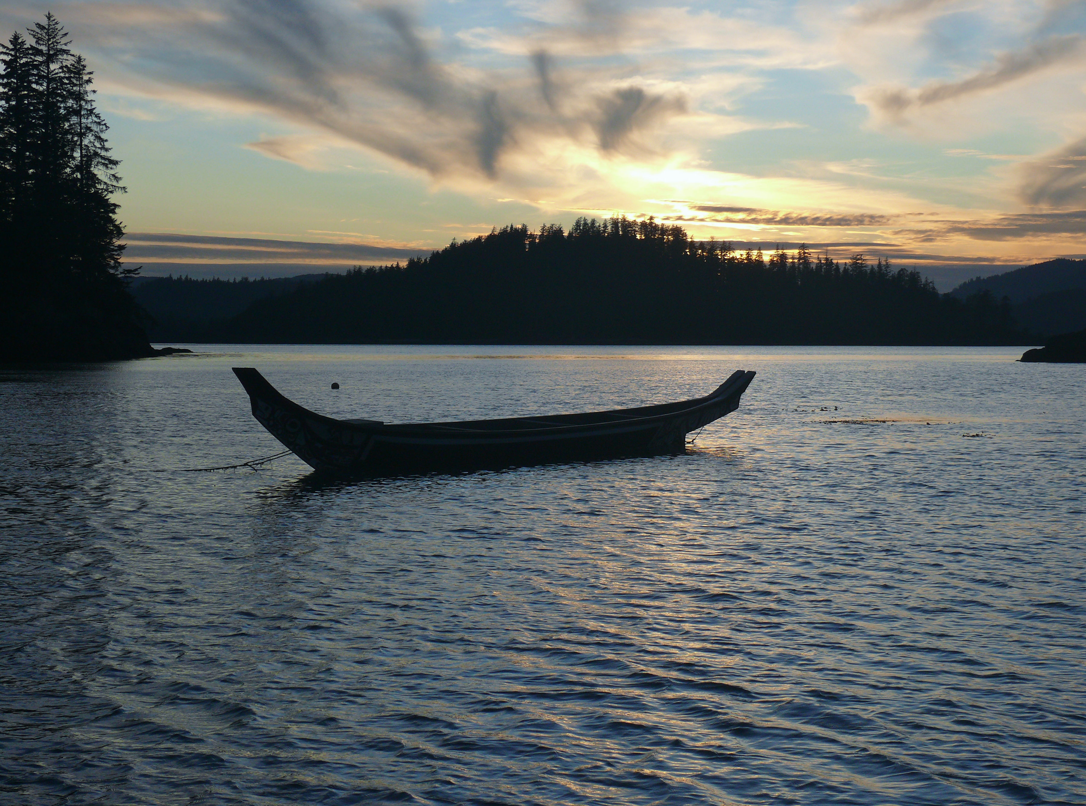 a canoe floats on calm waters at sunset