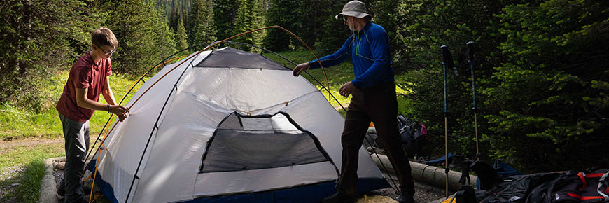 Deux campeurs montent leur tente dans le camping du Ruisseau-Numa, dans l’arrière-pays. 