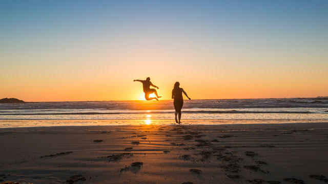 La silhouette de deux personnes se profile au coucher du soleil sur la plage 