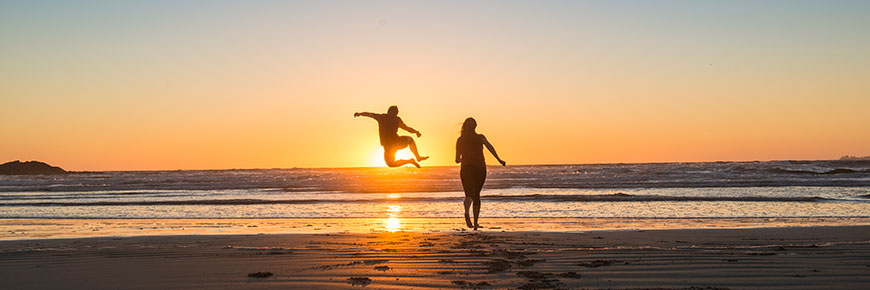 Deux personnes devant un coucher de soleil sur la plage Wickaninnish.