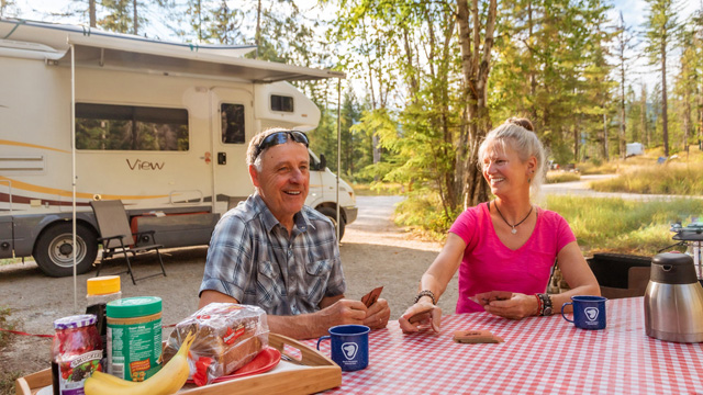 Two people sitting at a picnic table in a campground