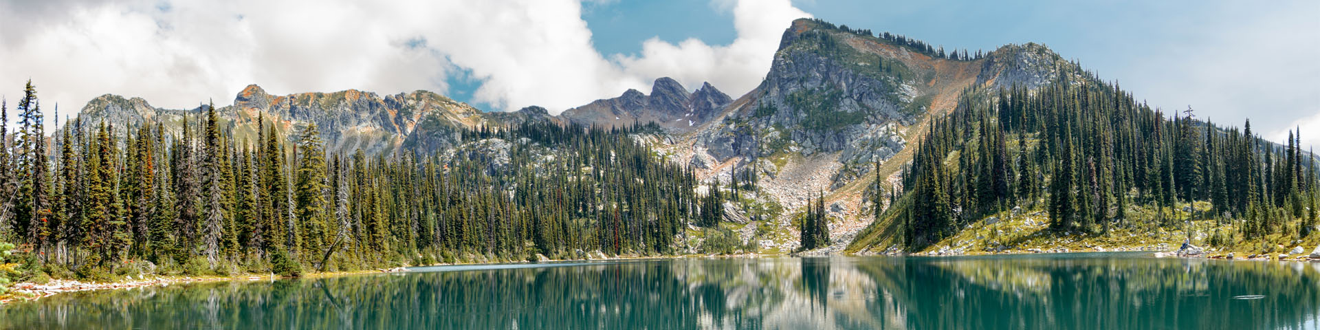 Photo de paysage d'un décor alpin avec un lac en forme de miroir au premier plan