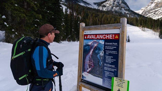 A backcountry skier reads an avalanche hazard sign at Emerald Lake in Yoho National Park.