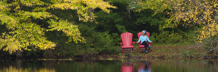 Une femme assise dans une chaise rouge tout près d'un lac