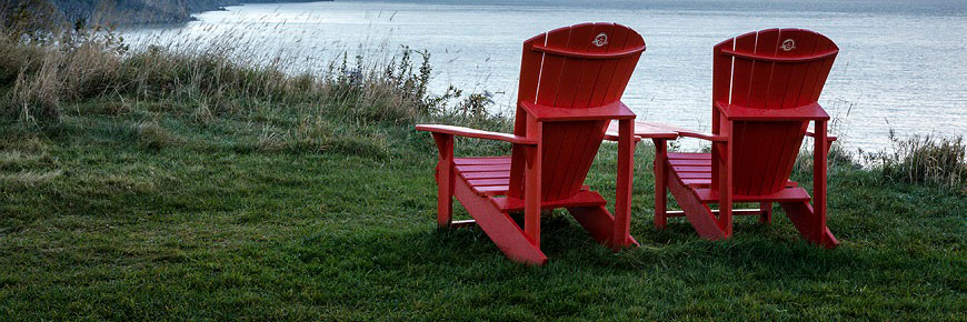 Des touristes, assises sur des chaises rouges, admirent le panorma sur la baie de Fundy