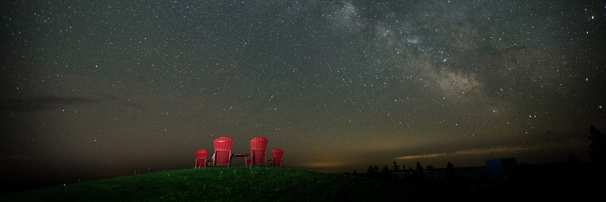 Four red chairs under a dark, starry sky