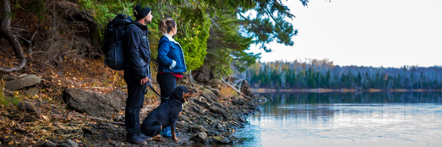 A couple and their dog on the side of the river