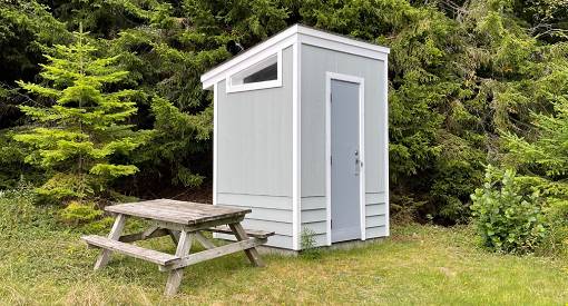 The outside of a washroom next to a picnic table