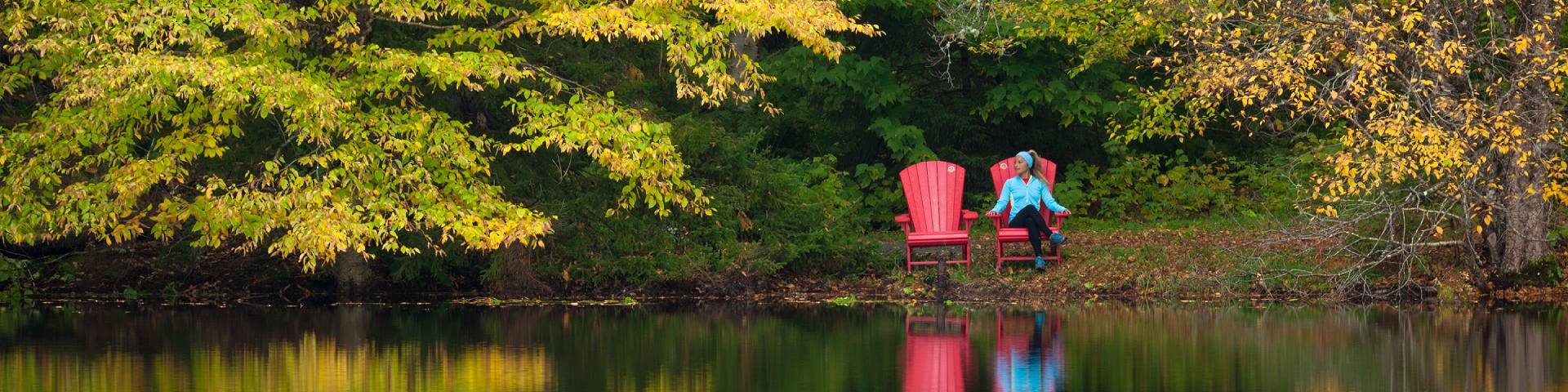 Une personne assise dans une chaise rouge tout près d'un lac