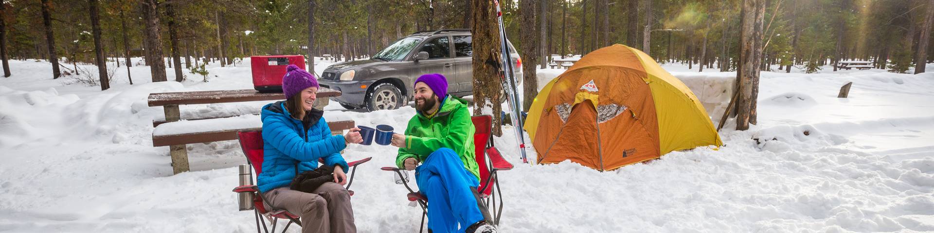 Un couple près d'une tente dans la neige