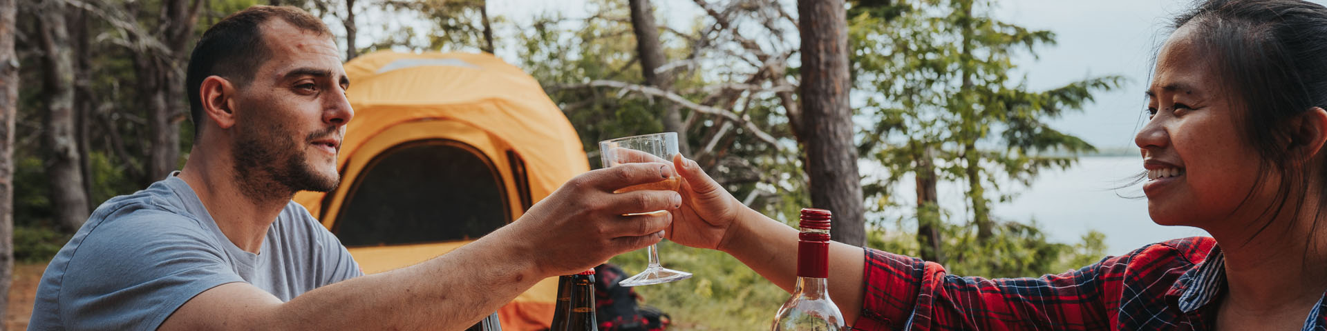 A couple have a drink near their tent.