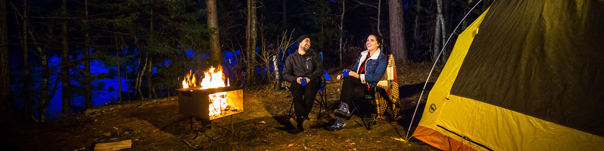 Un couple assis près du feu à leur emplacement de camping dans l'arrière-pays.