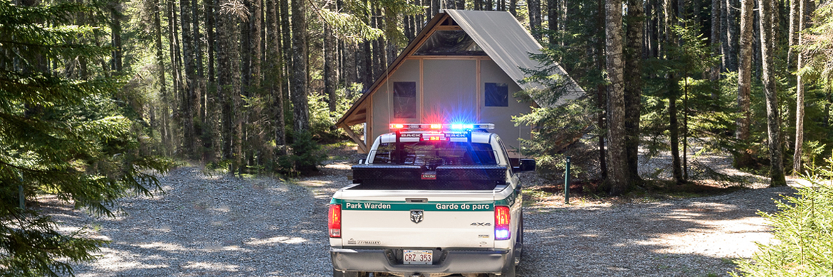 A Parks Canada Warden Service's truck with emergency lights flashing near an oTENTik accommodation
