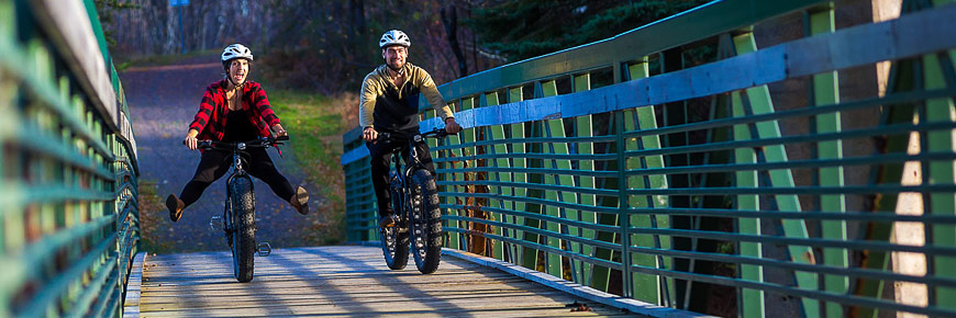 Un couple en vélo à pneus surdimentionné traversant un pont