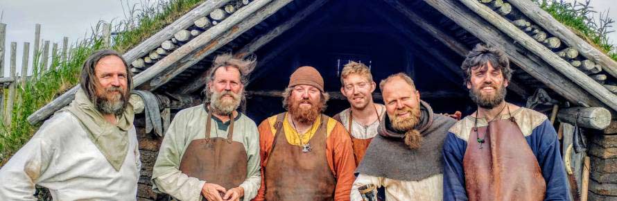 A group of vikings in front of a wooden shack