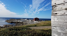 a red cabin on a rocky coastline