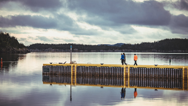 three people walking on a wooden wharf