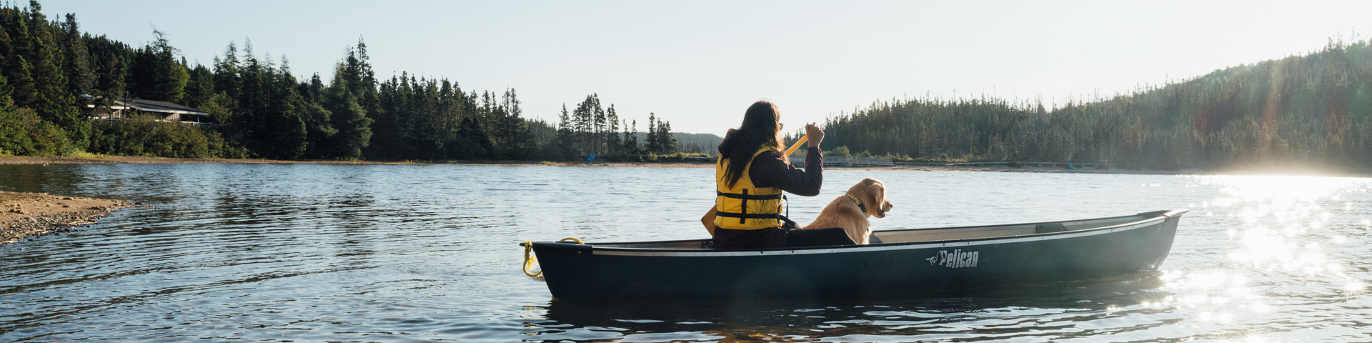 an individual and a dog in a canoe on a pond