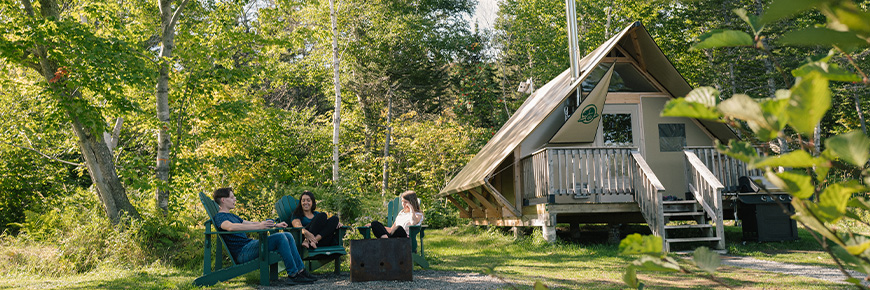 Three people sitting around a campfire next to an oTENTik