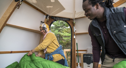two people setting up a green sleeping bag inside of an Ôasis