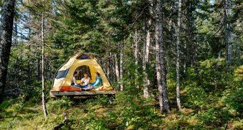 trois personnes dans une tente en forêt