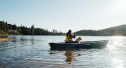 un individu et un chien dans un canoë sur un étang