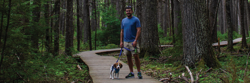 A man hikes with his dog on the Hemlocks and Hardwoods Trail in Kejimkujik.