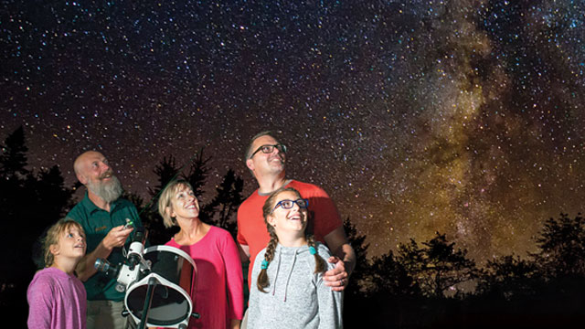 Une famille observe les étoiles avec un grand télescope. 