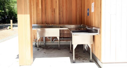 Outdoor dish-washing station with two sinks and taps for running water.