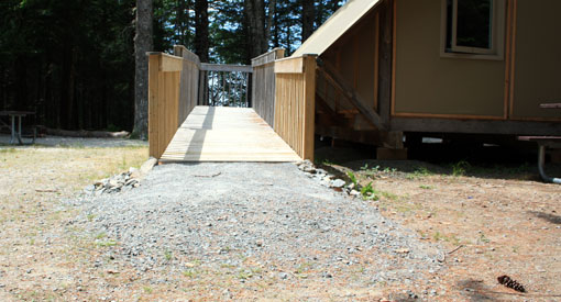 Gravier concassé et rampe d’accès en bois menant à une tente oTENTik facile d’accès 