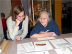 An archaeologist and an Inuvialuit Elder gather at a table to look at an Inuit artifact from the park.