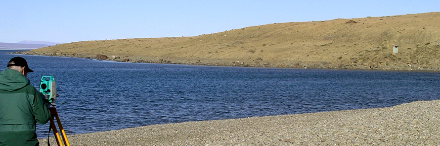 A person surveying beside a lake.