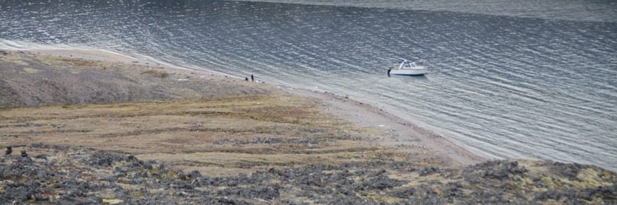 Un bateau près du rivage. Deux personnes marchent sur le rivage.