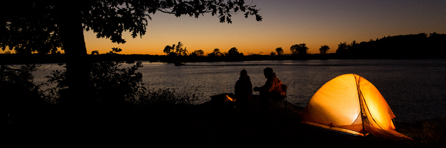 Deux visiteurs site à côté de leur tente au coucher du soleil